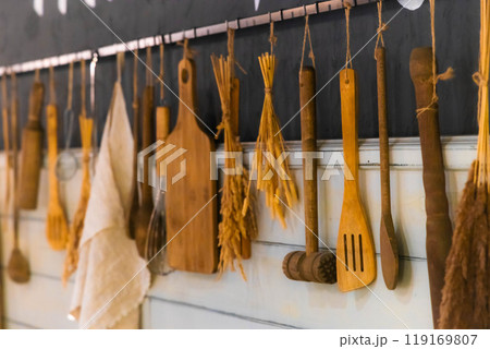 Rustic kitchen utensils arranged creatively on a wooden wall in a cozy cooking space filled with warmth Rustic kitchen utensils arranged creatively on a wooden wall in a cozy cooking space filled with warmth 119169807