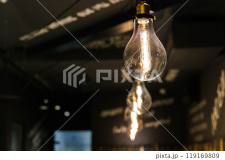 Elegant hanging light bulbs illuminate a modern cafe interior in a cozy atmosphere during the evening hours 119169809