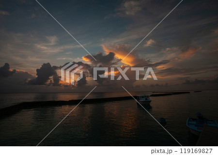 Stunning sunset over tranquil waters in Maldives with boats silhouetted against colorful clouds Stunning sunset over tranquil waters in Maldives with boats silhouetted against colorful clouds 119169827