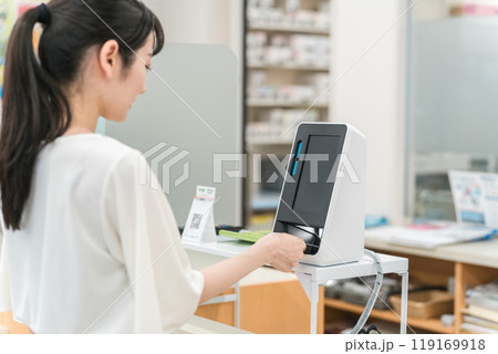 薬局・病院でマイナンバーカードをカードリーダーの機械で読み込む女性 119169918