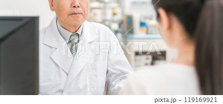薬局・ドラッグストアで薬・処方せんの相談をする女性と薬剤師の男性 119169921