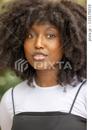 Confident woman with curls posing outdoors, expressing empowerment and beauty in urban setting 119170058