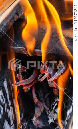 A fire burns in a campfire with a red fire in the background. 119171241