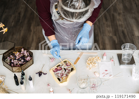 Craftsperson wearing safety gear while creating resin art with dried flowers. DIY home decor with focus on safety and sustainable materials. Craftsperson wearing safety gear while creating resin art with dried flowers. DIY home decor with focus on safety and sustainable materials. 119171490