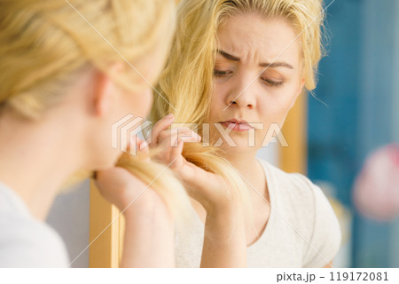 Woman having blonde split ends hair Woman having blonde split ends hair 119172081