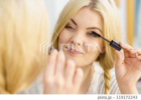 Woman using mascara on her eyelashes Woman using mascara on her eyelashes 119172243