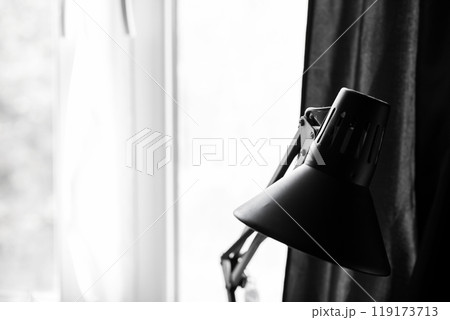 A beautiful black lamp is elegantly sitting in front of a black curtain 119173713