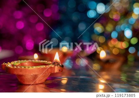 Diwali celebration background with glowing clay lamps and colorful lights. 119173805