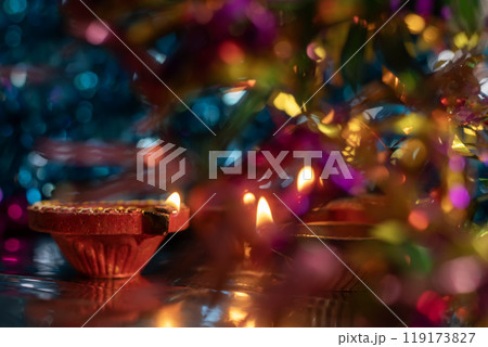 Diwali celebration background with glowing clay oil lamps and colorful lights bokeh 119173827