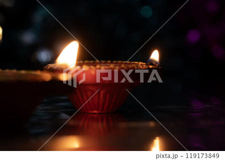 Traditional Diwali Diyas and beautiful light reflection with bokeh effect on dark background for Diwali festival celebration. Closeup 119173849
