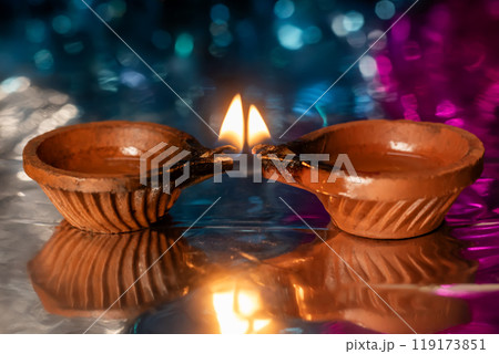 Diwali celebration lit clay lamp and light reflected on colorful background. 119173851