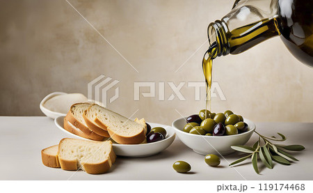 Olive oil is poured from a bottle into a bowl. There are slices of bread nearby. Olive oil is poured from a bottle into a bowl. There are slices of bread nearby. 119174468