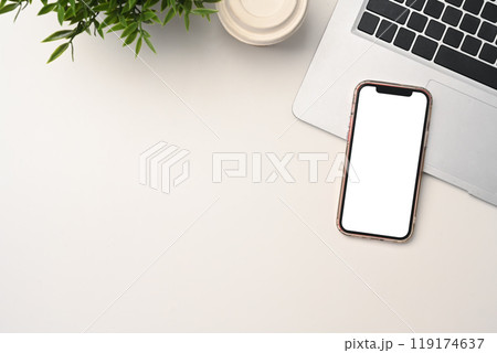 Mobile phone with blank screen, laptop, and paper cup of coffee on white table 119174637