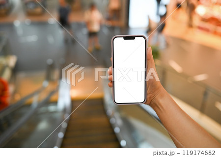 Hands holding a smartphone with blank white screen on blurred background of shopping mall 119174682