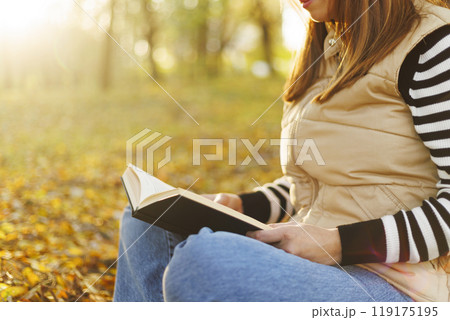 Person reading a book in autumn sunlight 119175195