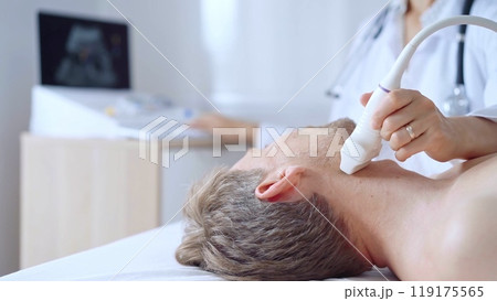 Doctor woman performing neck ultrasound exam on male patient. Medicine service concept. Thyroid gland health Doctor woman performing neck ultrasound exam on male patient. Medicine service concept. Thyroid gland health 119175565