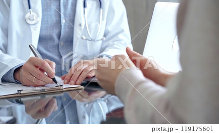 Doctor man is making notes while consulting patient with clipboard and a pen in his hand in medical office. Trust concept in Medicine 119175601