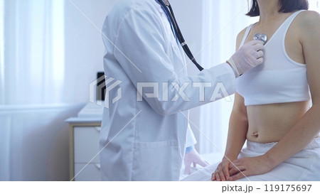 Doctor and patient. Physician wearing white medical gloves is using stethoscope examining woman lungs in clinic. Medicine concept 119175697