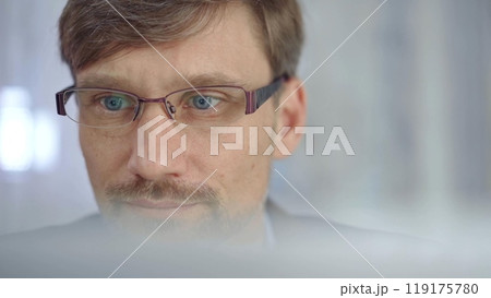 Businessman with glasses looking intently obscured partially by a translucent surface of laptop. Business people concept Businessman with glasses looking intently obscured partially by a translucent surface of laptop. Business people concept 119175780