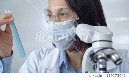 Female scientist analyzing sample of a test tub in laboratory setting. Science concept Female scientist analyzing sample of a test tub in laboratory setting. Science concept 119175941