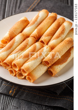 Cigarette Russes or Russian cigarettes are homemade thin cookies closeup on the plate. Vertical Cigarette Russes or Russian cigarettes are homemade thin cookies closeup on the plate. Vertical 119177163