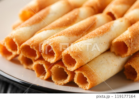 Sweet Russian cigarettes are tender tubes baked to a crispy golden crust close-up in a plate. Horizontal Sweet Russian cigarettes are tender tubes baked to a crispy golden crust close-up in a plate. Horizontal 119177164