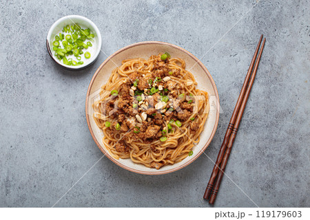Dan dan noodles served with chopsticks and green onions top view, traditional Chinese Sichuan dish Dan dan noodles served with chopsticks and green onions top view, traditional Chinese Sichuan dish 119179603