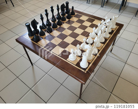 There is a chess table with chess pieces in the hall There is a chess table with chess pieces in the hall 119181055