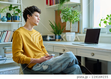 Young handsome guy using smartphone sitting, at home Young handsome guy using smartphone sitting, at home 119184155