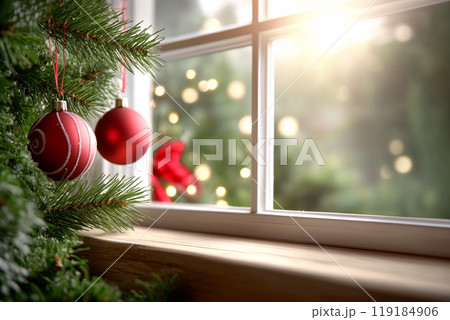 Red Christmas ornaments hanging on frosted branches beside a window with a snowy view outside. Concept of holiday decor Red Christmas ornaments hanging on frosted branches beside a window with a snowy view outside. Concept of holiday decor 119184906