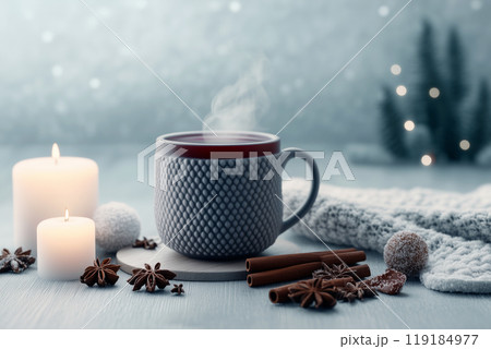 A steaming cup of coffee beside a candle on a soft surface, creating a cozy atmosphere 119184977
