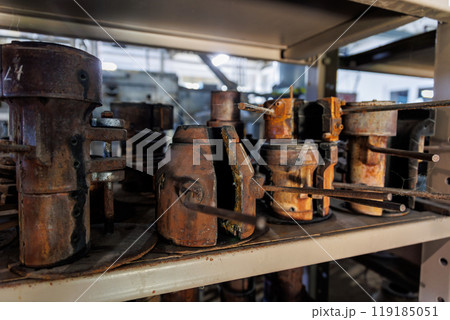 Close-up view of old, rusted metal molds on a shelf in an industrial workshop, showing signs of wear and decay, evoking a sense of history and craftsmanship 119185051