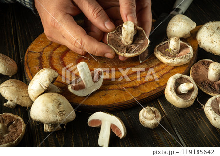 Male hands holding champignon or agaricus mushroom. Sorting and cleaning mushrooms on the kitchen table before adding to food Male hands holding champignon or agaricus mushroom. Sorting and cleaning mushrooms on the kitchen table before adding to food 119185642