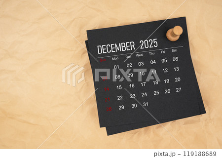 Black calendar sheet for December 2025 with thumbtack on brown paper crumpled. 119188689
