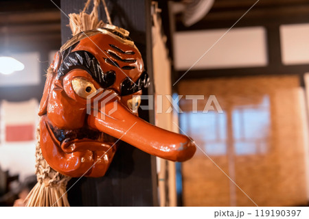 Red Japanese Tengu Mask hang on wood pillar in Japanese building 119190397