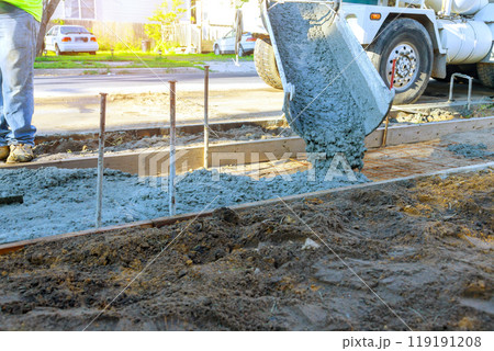 Concrete mixer truck pouring fresh concrete over reinforced bars for construction of new sidewalk Concrete mixer truck pouring fresh concrete over reinforced bars for construction of new sidewalk 119191208