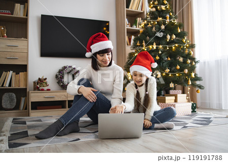 Mother and daughter using laptop during festive holiday season Mother and daughter using laptop during festive holiday season 119191788