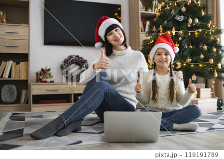 Mother and daughter celebrating Christmas together with computer 119191789