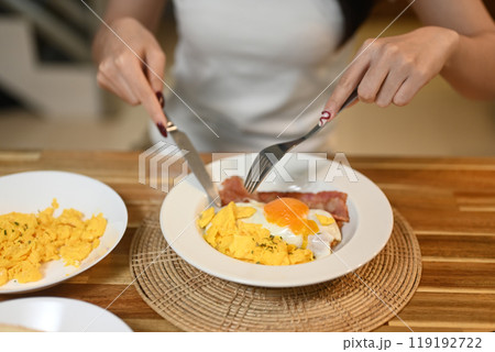Close up shot of woman eating breakfast on wooden kitchen counter 119192722