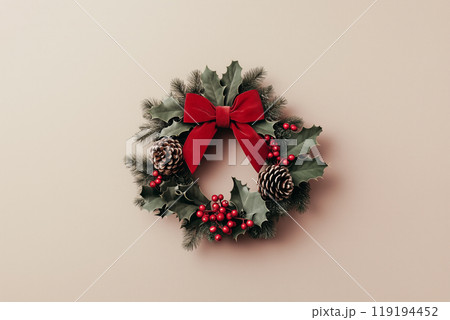 Festive Christmas wreath adorned with pine cones, red berries, and a red bow, set against a beige background. 119194452