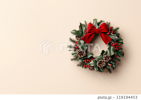 Festive Christmas wreath adorned with pine cones, red berries, and a red bow, set against a beige background. 119194453