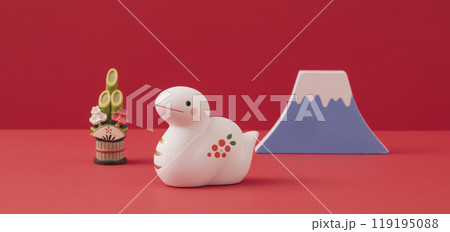 お正月。干支の巳（ヘビ）。赤背景上の巳の置物と富士山と門松。 119195088