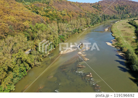 Aerial view of illegal exploitation of river sand and gravel with excavator on river bank 119196692