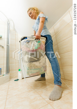 Woman holding laundry basket full of clothes Woman holding laundry basket full of clothes 119197269
