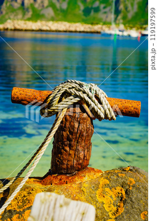 Old rusty mooring bollard with rope. Old rusty mooring bollard with rope. 119197599