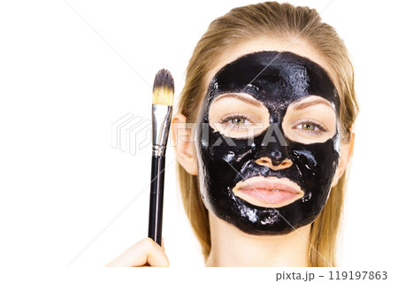 Woman applying black mud mask to face Woman applying black mud mask to face 119197863