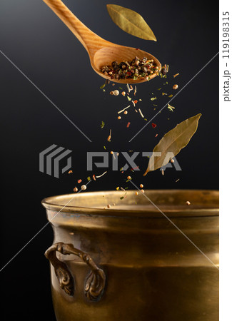 Mix of dried spices is poured into a old brass pan. 119198315