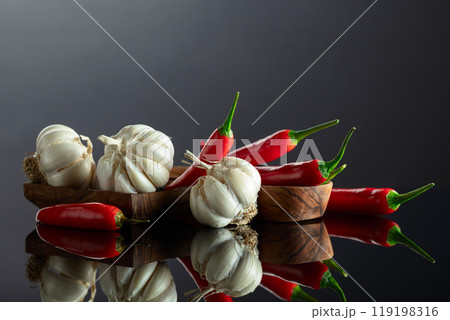 Garlic bulbs and red chili peppers on a black background. 119198316