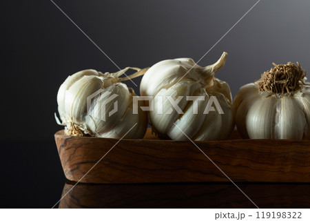 Garlic bulbs in wooden dish on a black background. 119198322