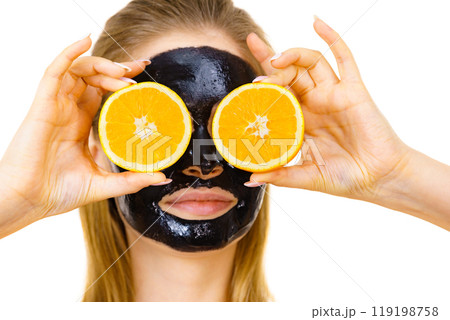 Girl black carbo mask on face holds orange fruit 119198758